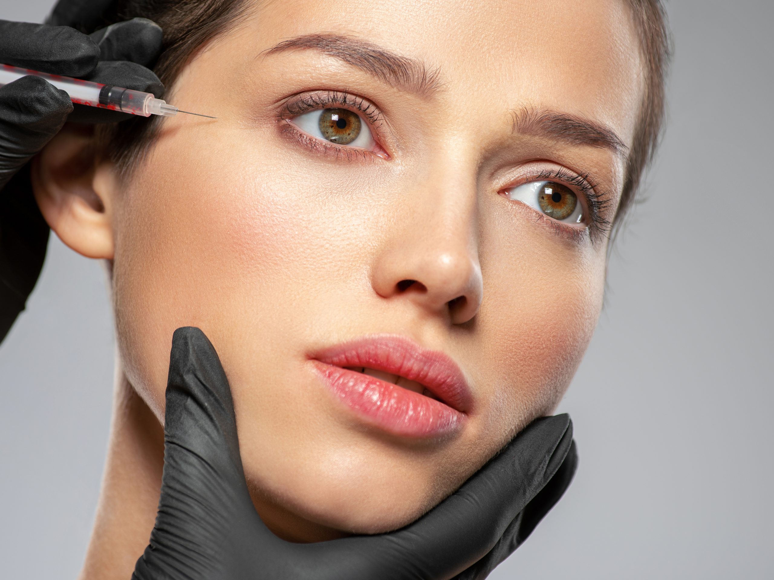 Mujer joven inyectando botox cerca de los ojos